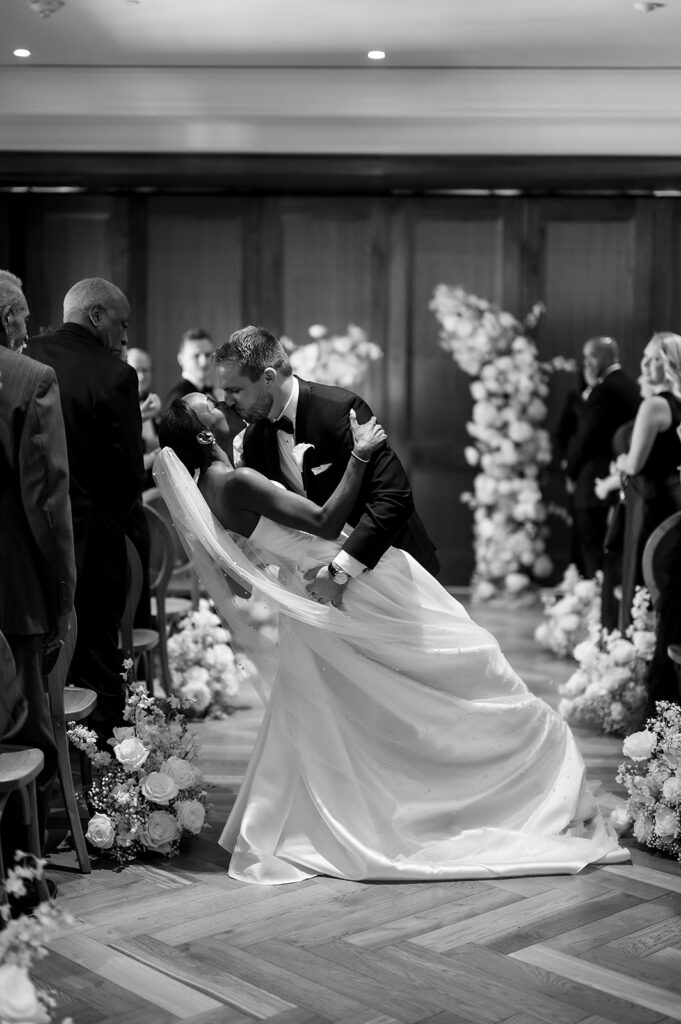 Bride and groom ends of aisle kiss during their Book Tower wedding ceremony in The Linden Room
