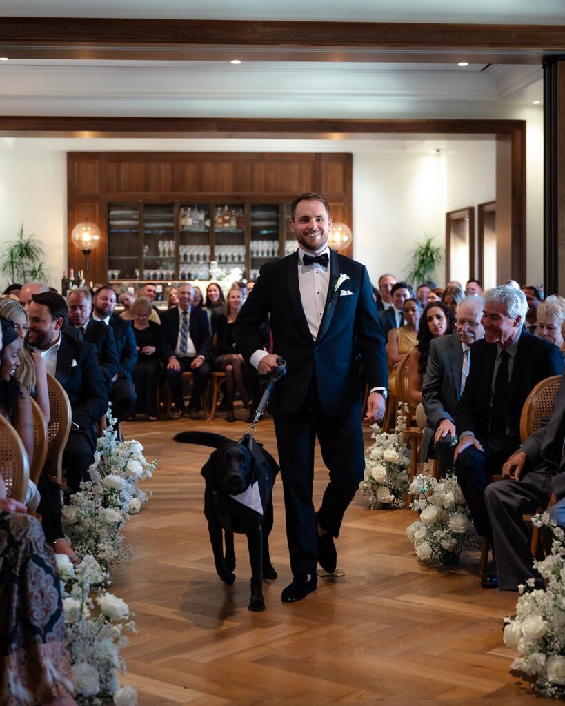 Groom walking down the aisle with his dog