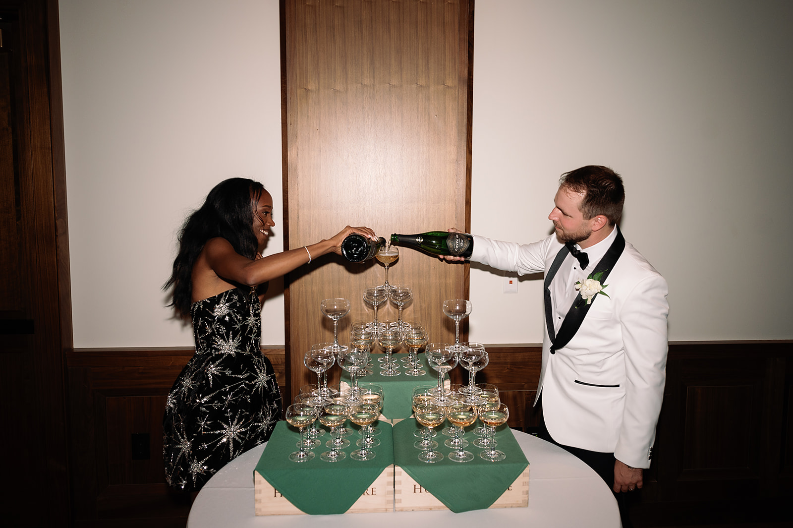Bride and groom pouring into their champagne tower during their Book Tower wedding reception