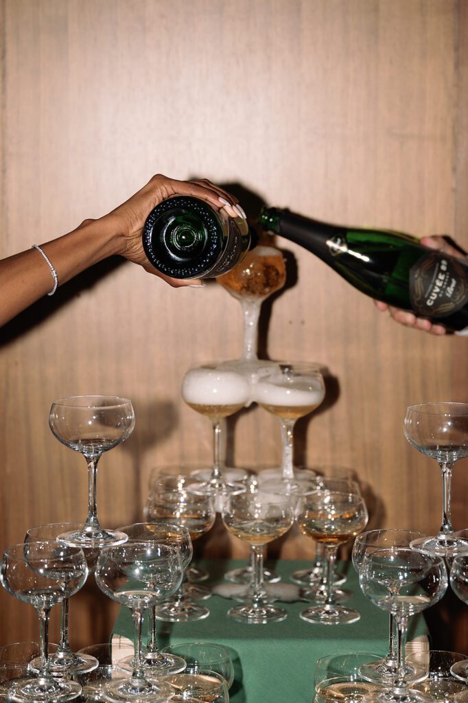 Bride and groom pouring into their champagne tower during their Book Tower wedding reception