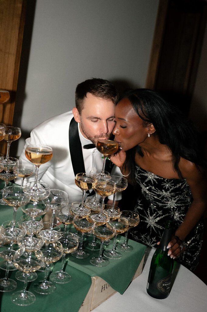 Bride and groom drinking from their champagne tower during their Book Tower wedding reception