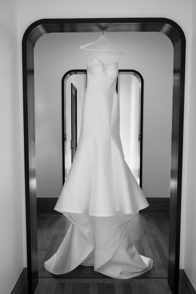 Black and white photo of a brides wedding dress hanging