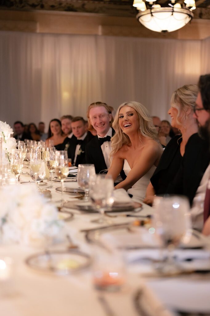 Bride and groom smiling during speeches