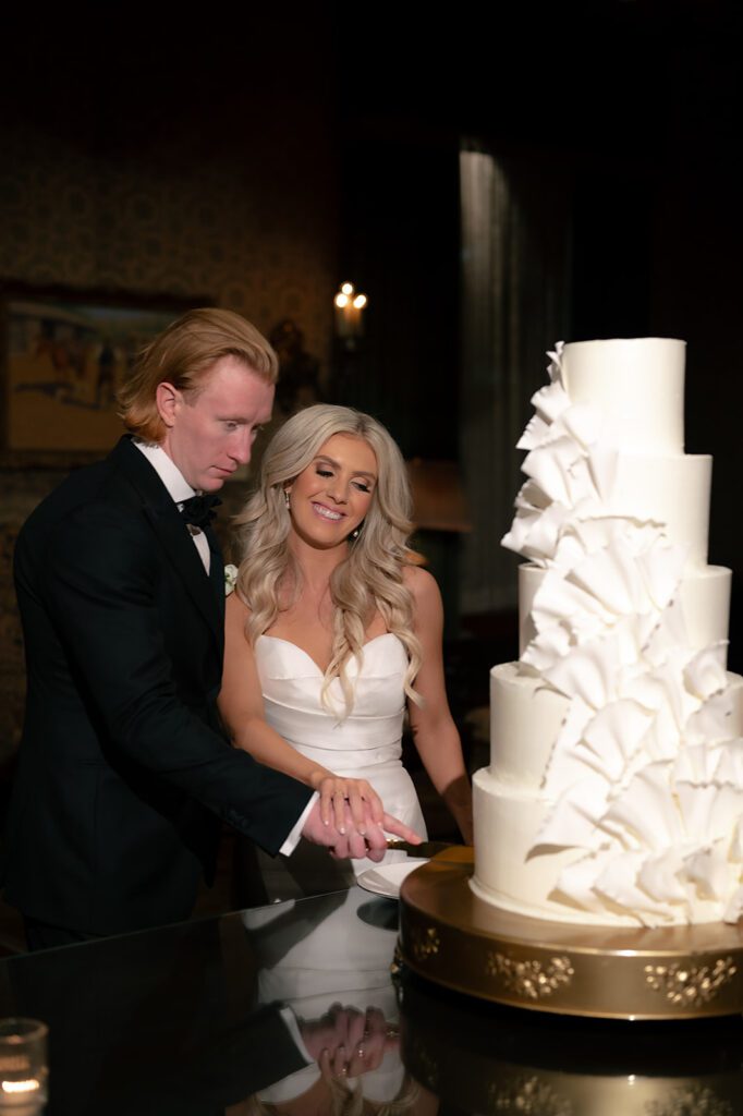 Bride and groom cutting into their 5 tiered white wedding cake