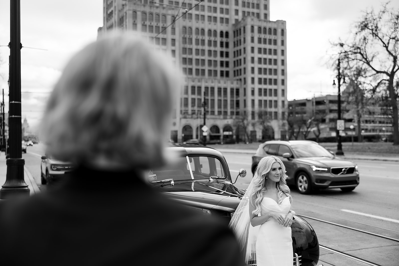 Bride posing for portraits as her groom watches her