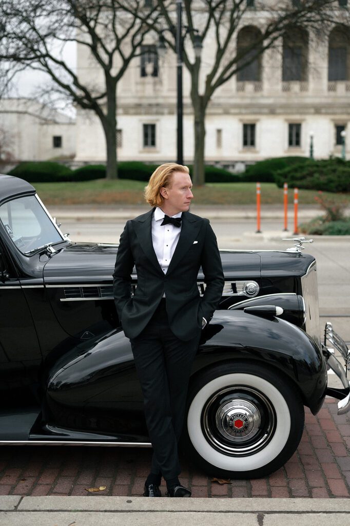 Groom posing with a 1940 Detroit Packard