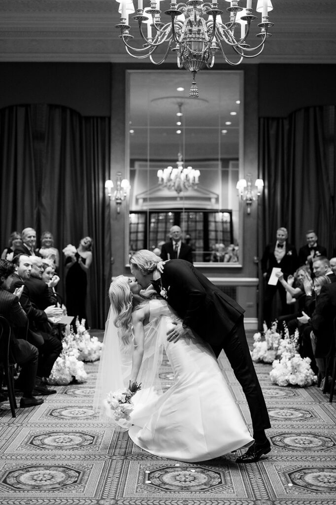 Bride and grooms end of aisle dip kiss during their Detroit Athletic Club wedding ceremony