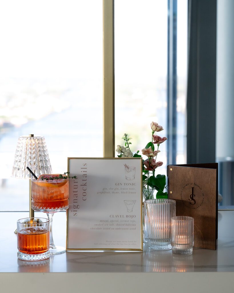 Elegant cocktail hour display at an MDRD Grand Plaza wedding, featuring signature drinks, glassware, florals, and a custom drink menu.