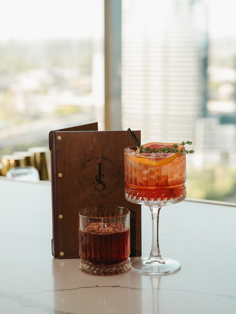 Two signature cocktails with a branded leather menu on display at an MDRD Grand Plaza wedding reception.