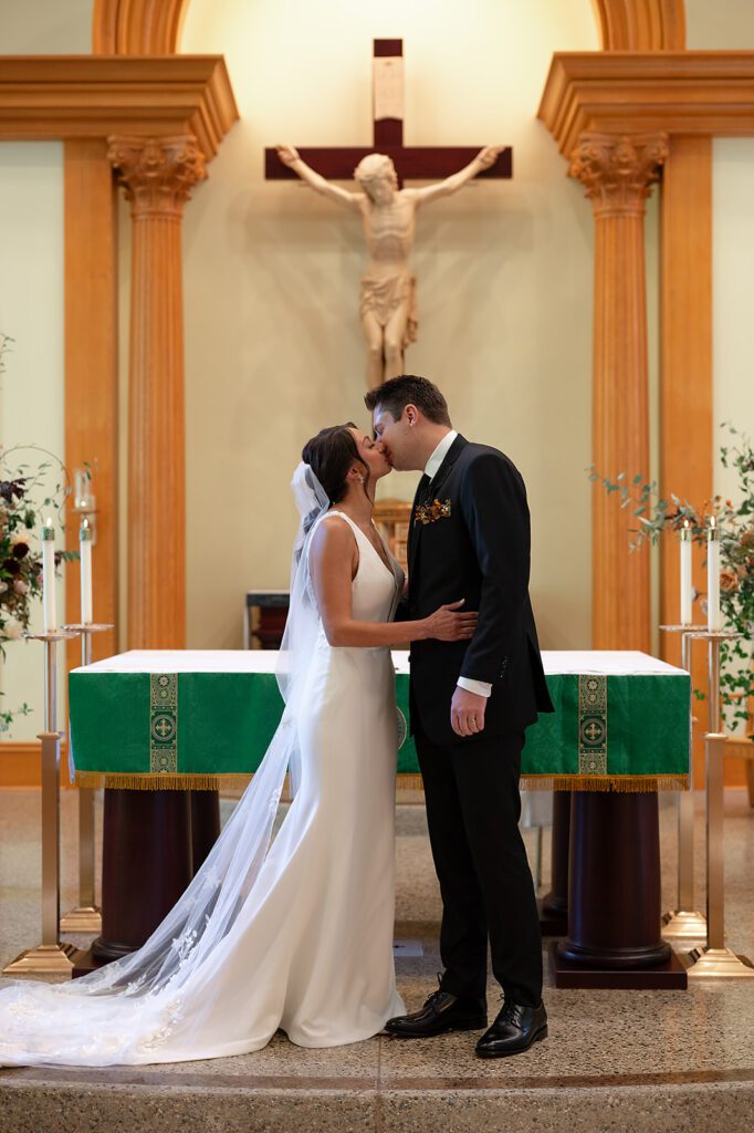Bride and groom kissing during their Grand Rapids Wedding Ceremony at Our Lady Seat of Wisdom Chapel on Aquinis College