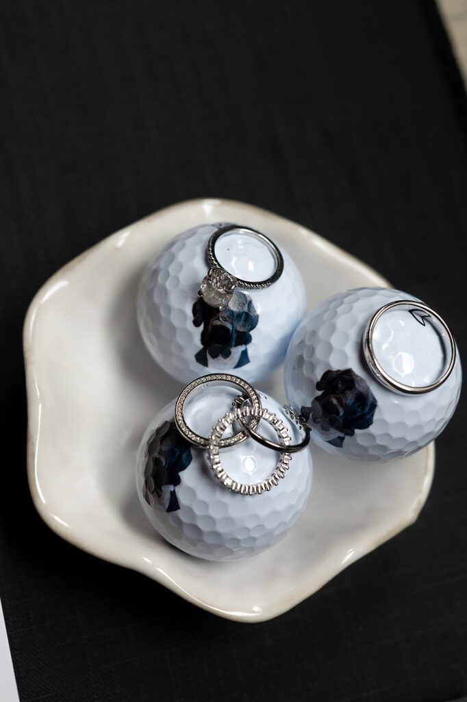 Unique wedding details with rings and custom golf balls with the bride and grooms dog on them by Vice Golf