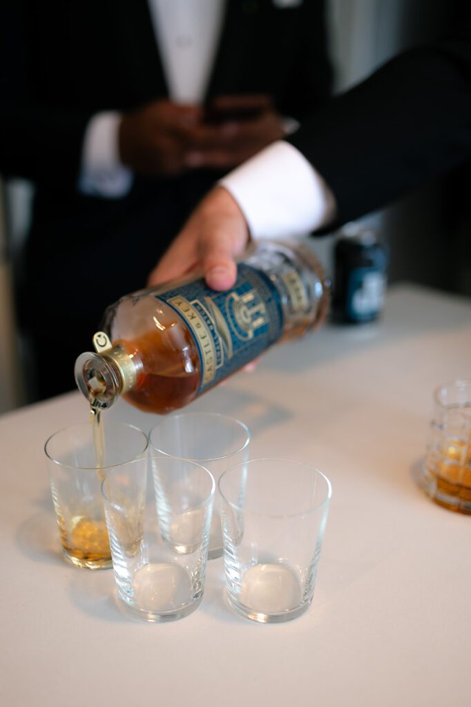 Groom pouring shots of whiskey