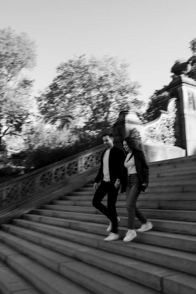 Black and white motion blur photo of a couple walking down the Bethesda Terrace steps.