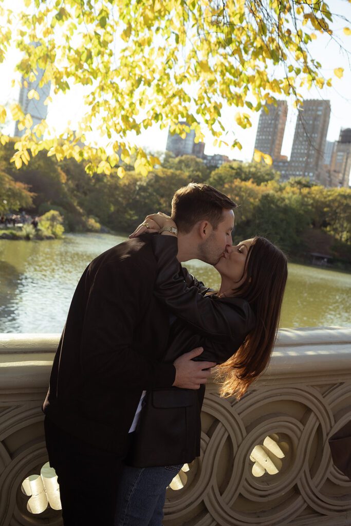 Couple kissing on Bow Bridge for their fall NYC engagement photos