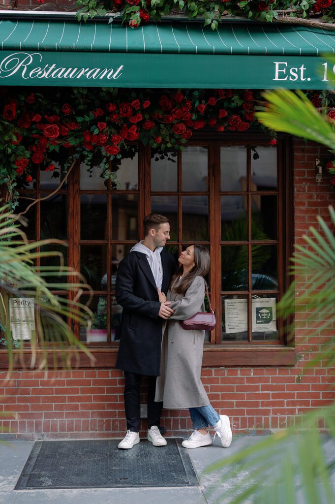 Couple posing for photos outside of a brick wall restaurant in Greenwich Village
