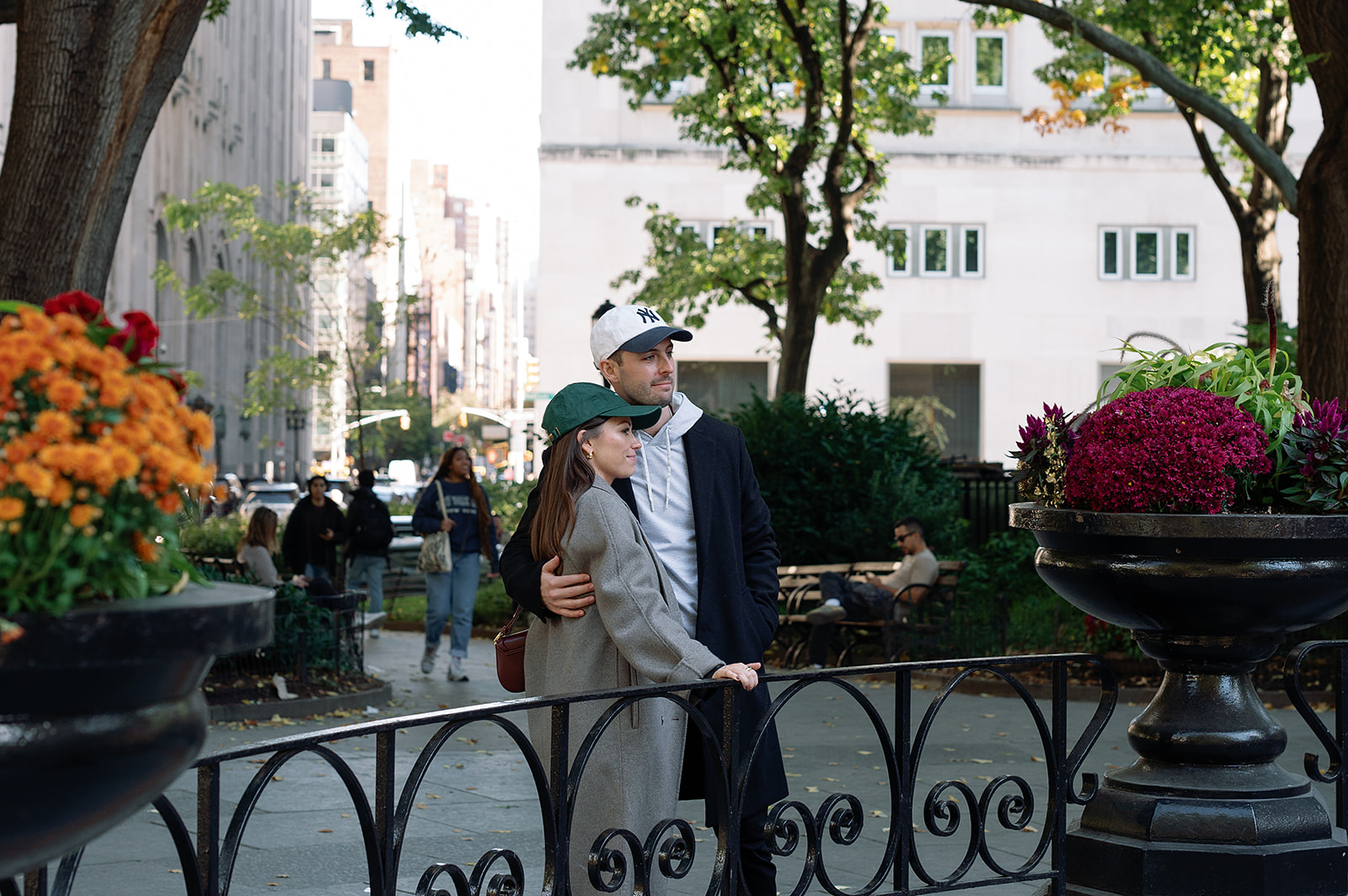 Couple standing arm in arm near colorful fall flowers in Greenwich Village during their engagement session.