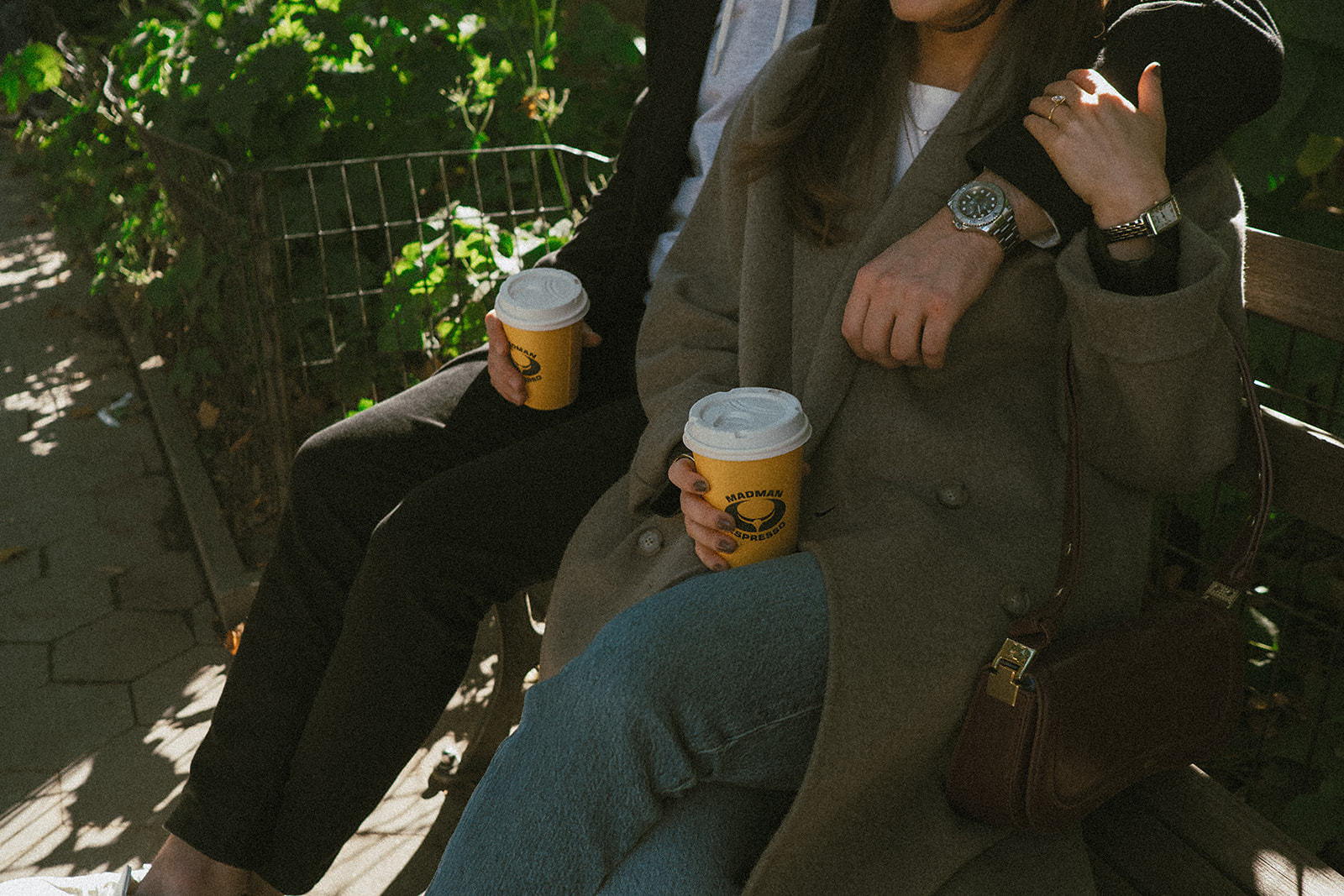 Close-up of coffee cups from Madman Espresso in the couple’s hands during their NYC engagement photos.