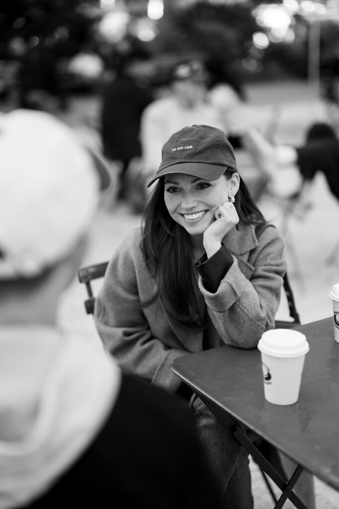 Black and white portrait of a woman smiling at her partner over coffee during their Greenwich Village engagement photos.