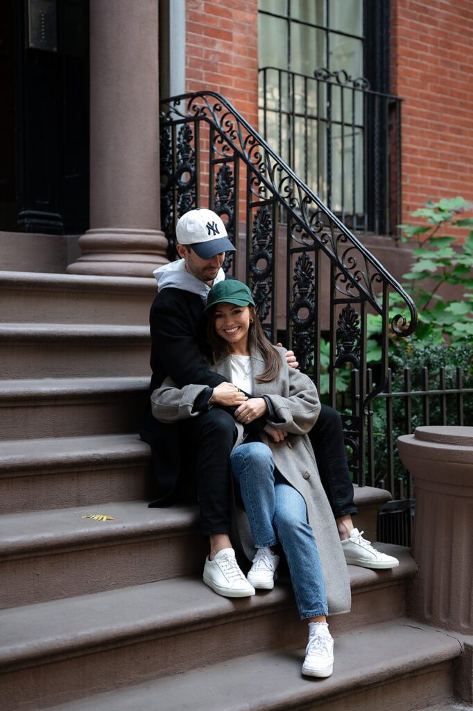 Couple sitting on brownstone steps during their Greenwich Village engagement photos.