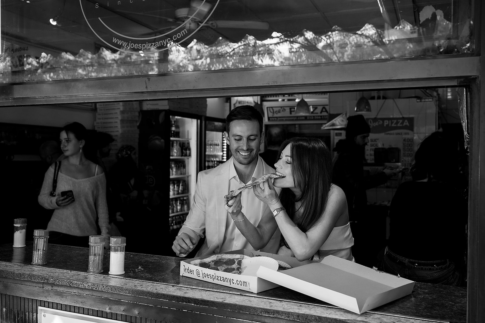 Black and white photo of couple eating pizza together at Joe’s Pizza in New York.