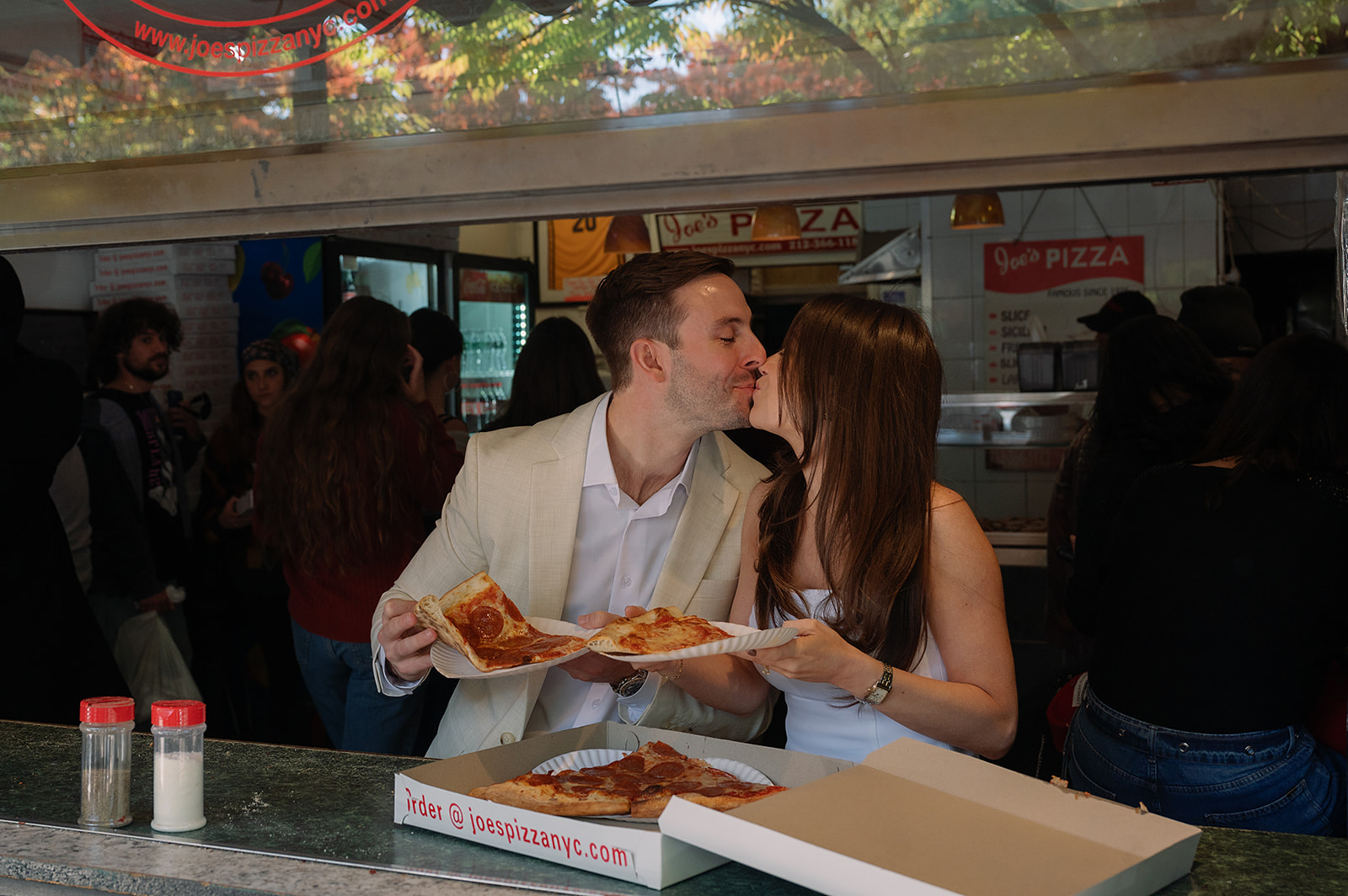 Couple kissing while eating pizza together at Joe’s Pizza in New York.