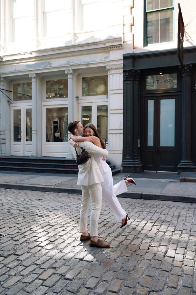Man picking up his fiance during their NYC engagement photos in SoHo