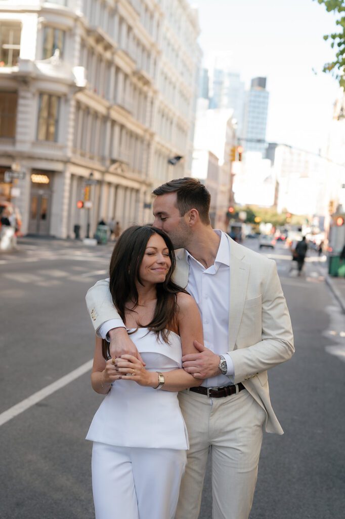 Man kissing his fiancés head during their NYC engagement photos in SoHo