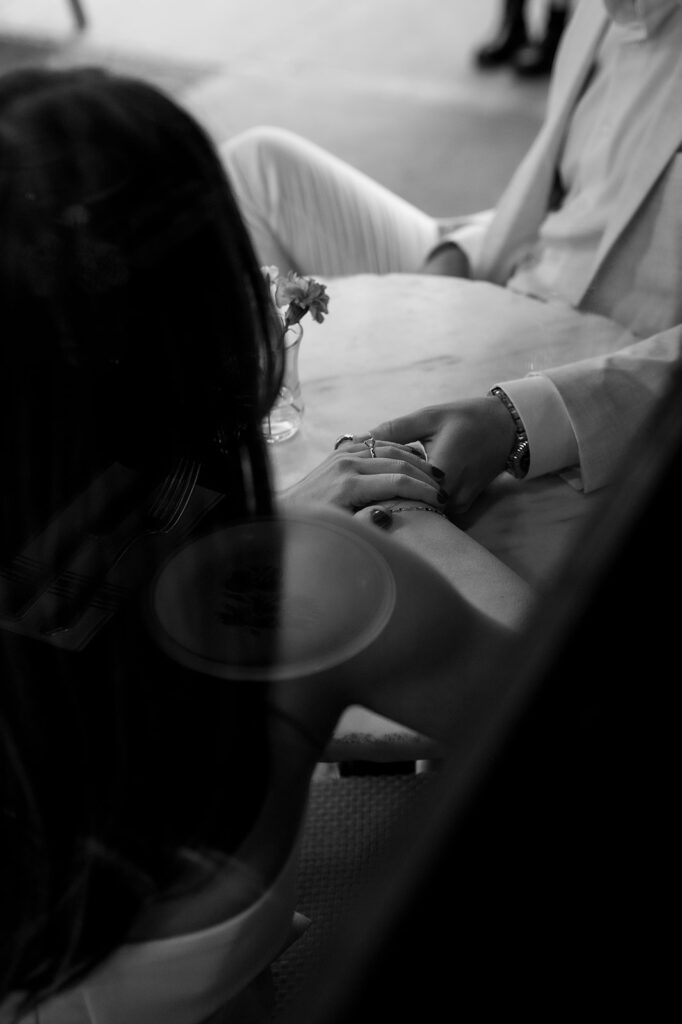Black and white photo of couple holding hands at a café table in SoHo.