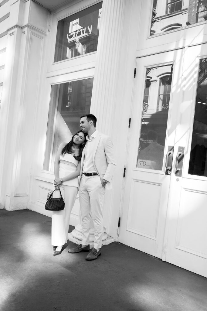 Black and white photo of couple leaning together outside a SoHo storefront.