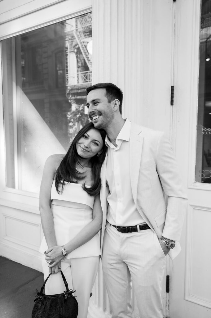 Black and white photo of couple leaning together outside a SoHo storefront.