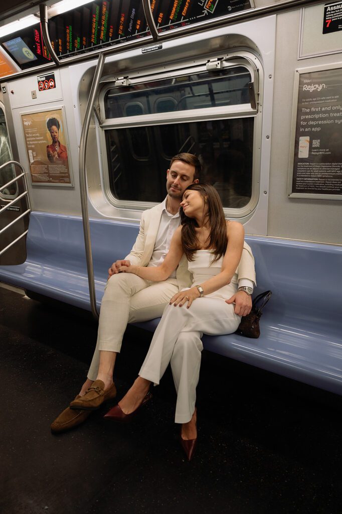 Couple sitting together on subway bench, one leaning on the other’s shoulder.