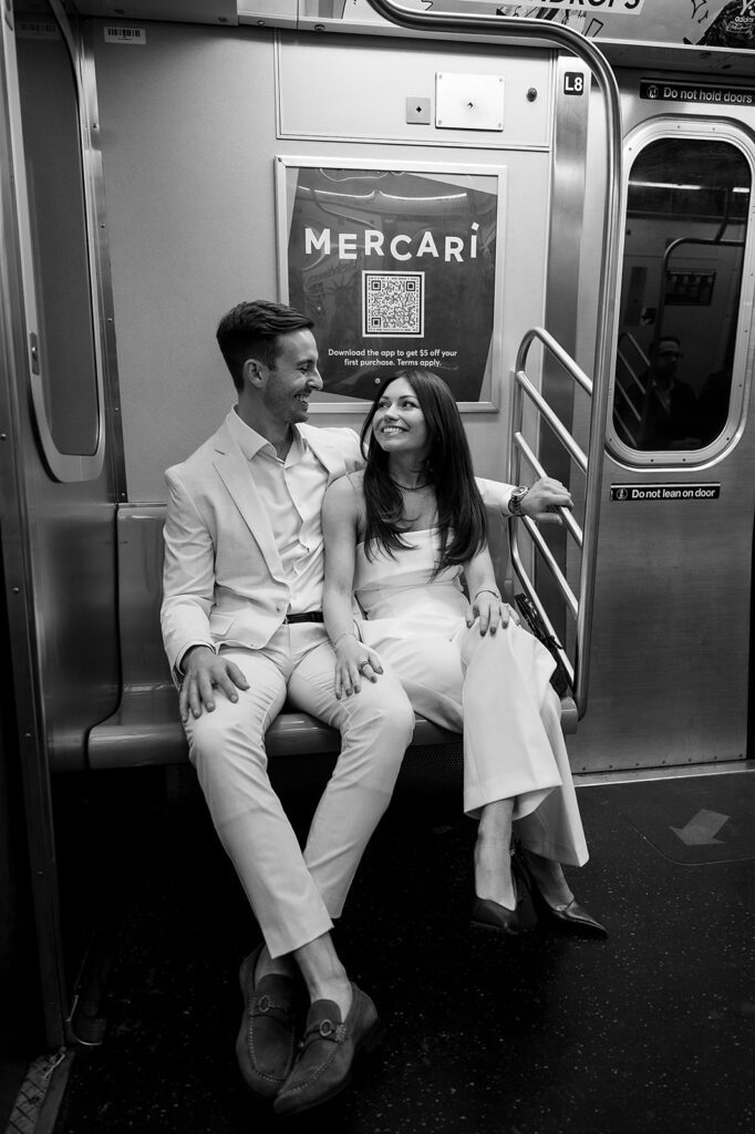 Couple sitting on a subway seat laughing together during engagement session.