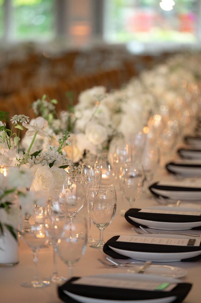 Lange Center Ballroom reception tables at Bay Harbor Yacht Club, featuring long floral centerpieces and candlelight.