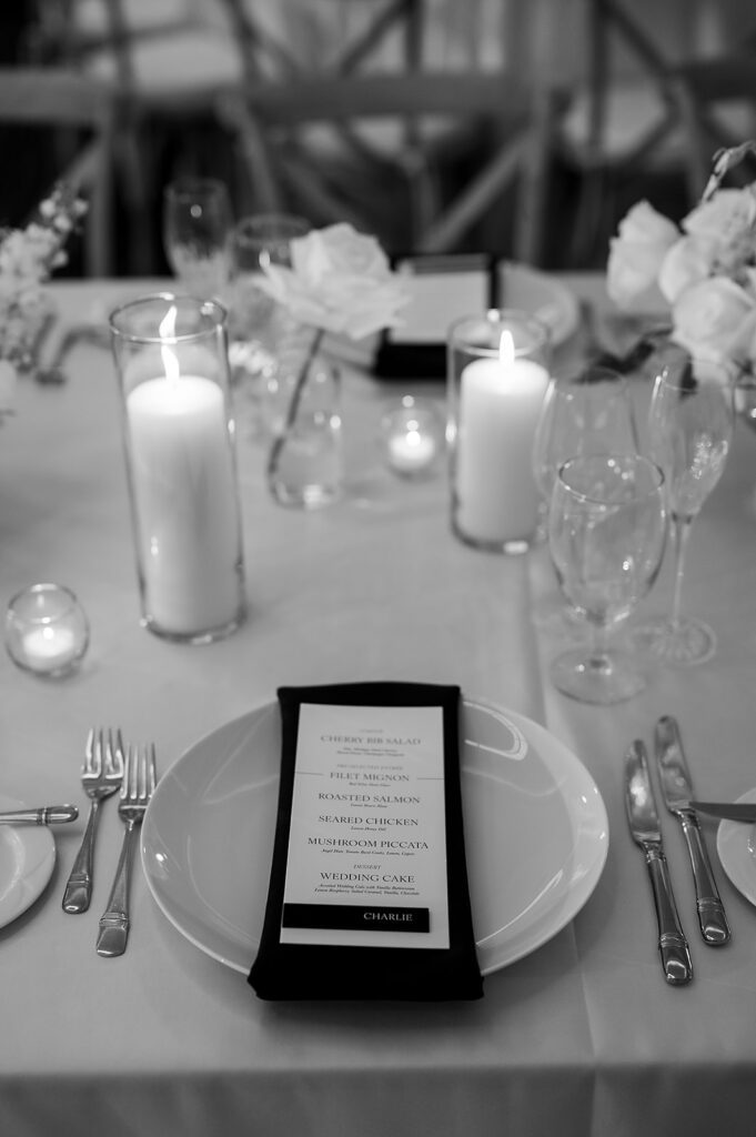 Elegant Bay Harbor Yacht Club wedding reception table decorated with white florals, candles, and black napkins in the Lange Center Ballroom.