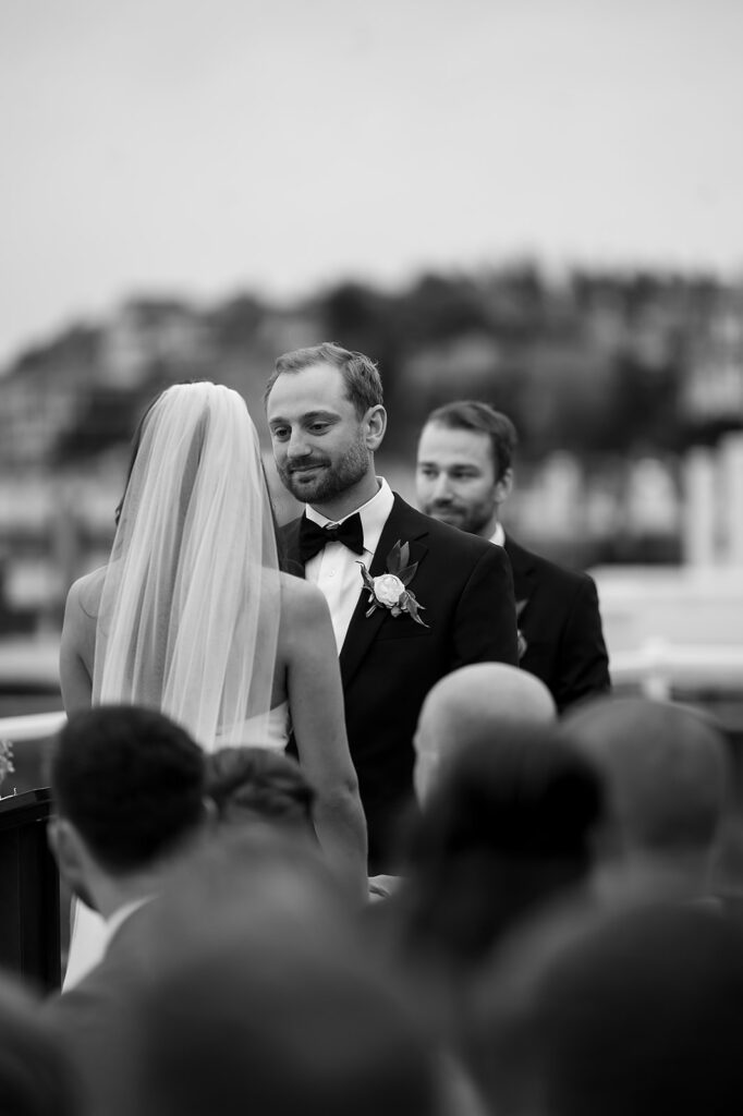 Black and white photo of the groom looking at his bride during their Bride and groom kissing during their Bay Harbor Yacht Club Promenade Dock wedding ceremony