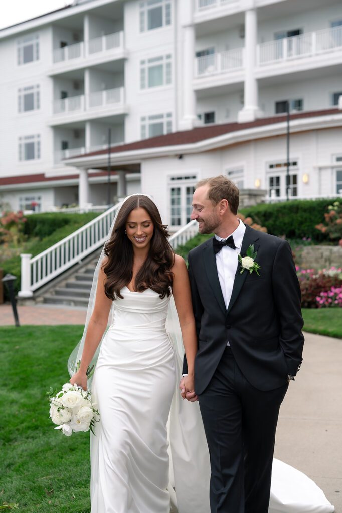 Couple walking hand in hand through the gardens at Bay Harbor Yacht Club surrounded by flowers.