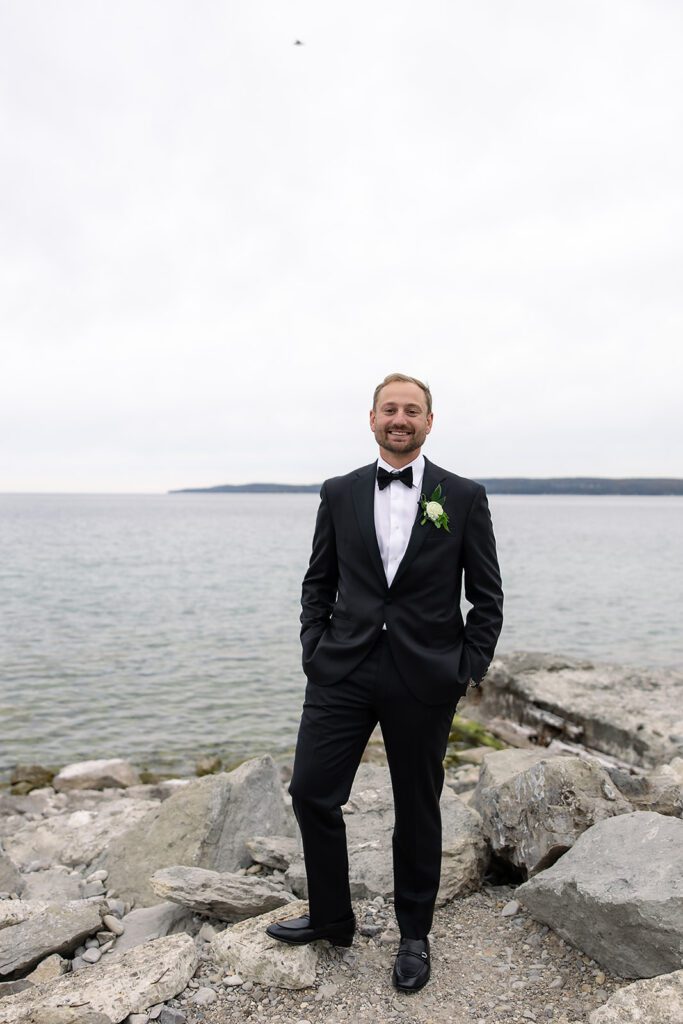 Groom posing with Little Traverse Bay in the background