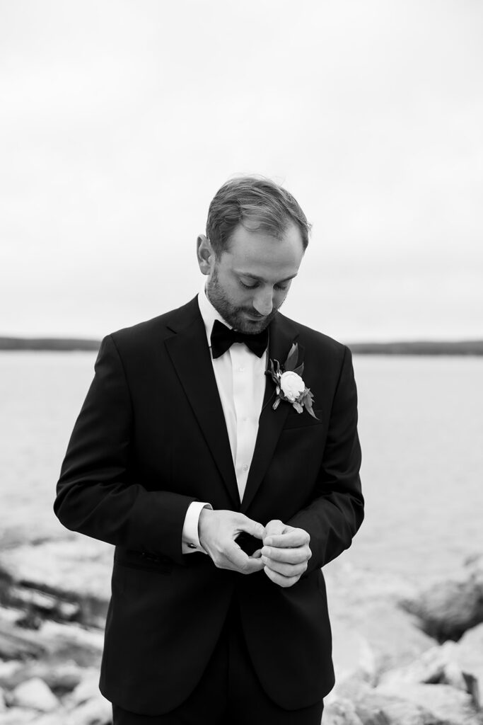 Black and white photo of a groom with Little Traverse Bay in the background