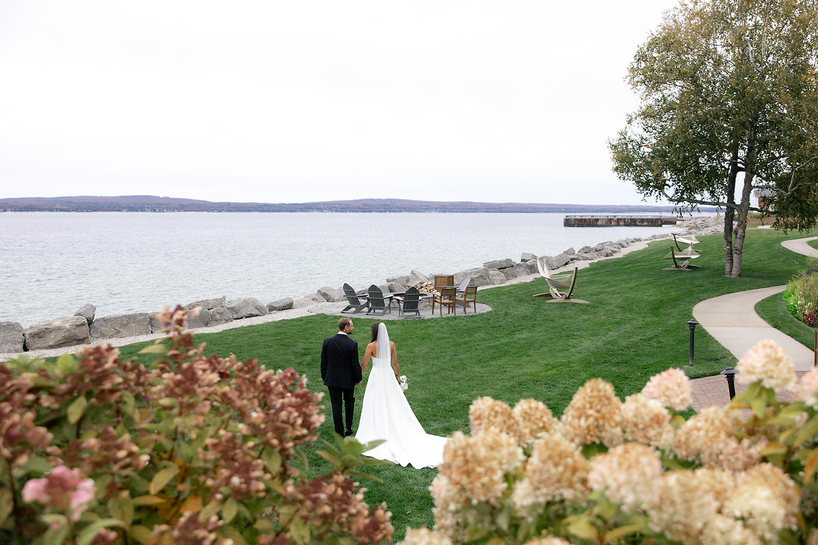 Bride and groom walking along the shoreline of Little Traverse Bay during portraits.