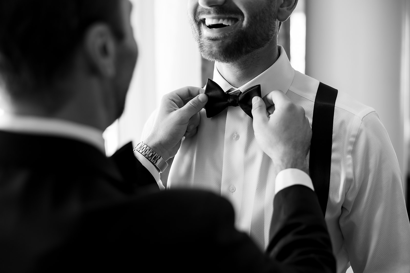 Black and white close up photo of the groom getting his bow adjusted 