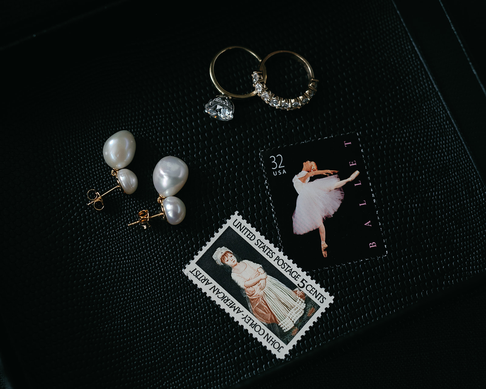Flat lay of wedding jewelry and vintage postage stamps styled before the ceremony.
