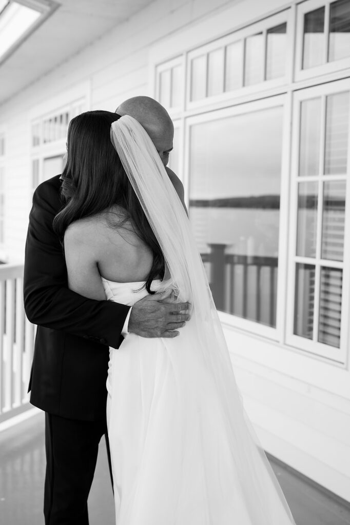 Father hugging the bride during an emotional first look on the balcony.