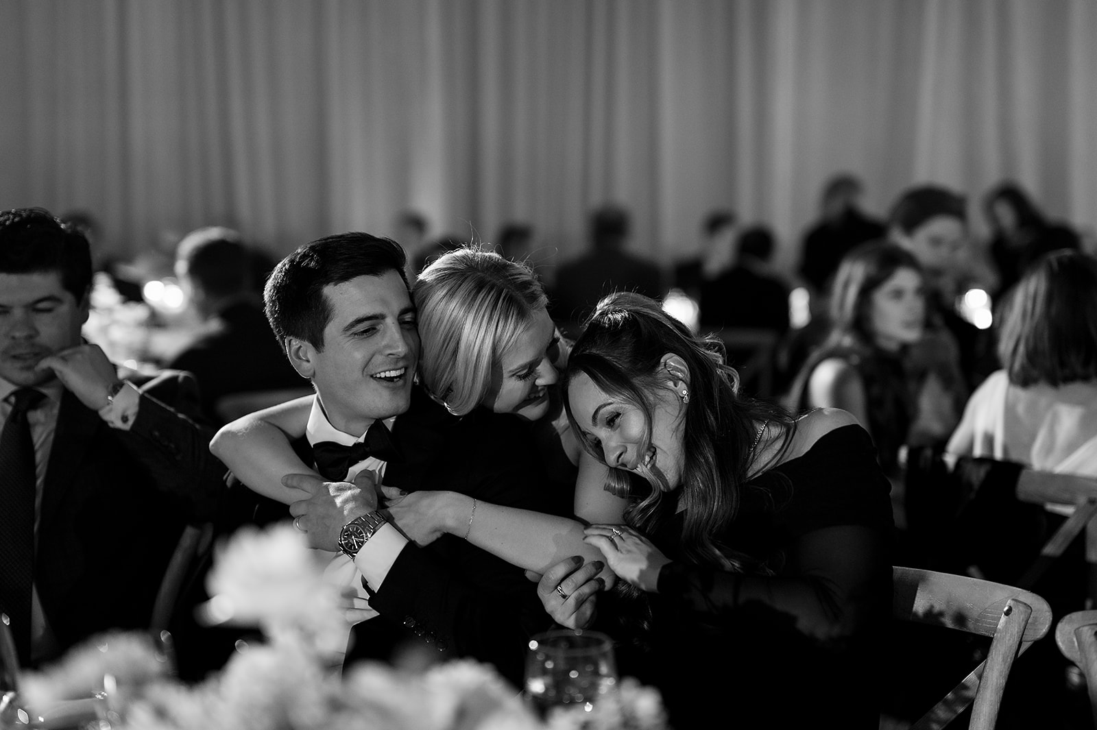 Candid black and white photo of guests hugging during the reception