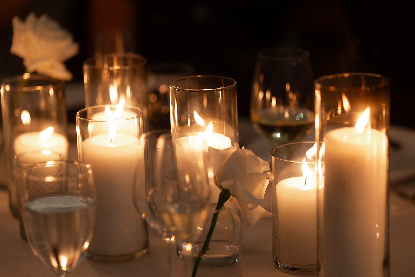 Candlelit glass votives and white roses creating a warm, romantic glow at the Bay Harbor Yacht Club wedding reception.