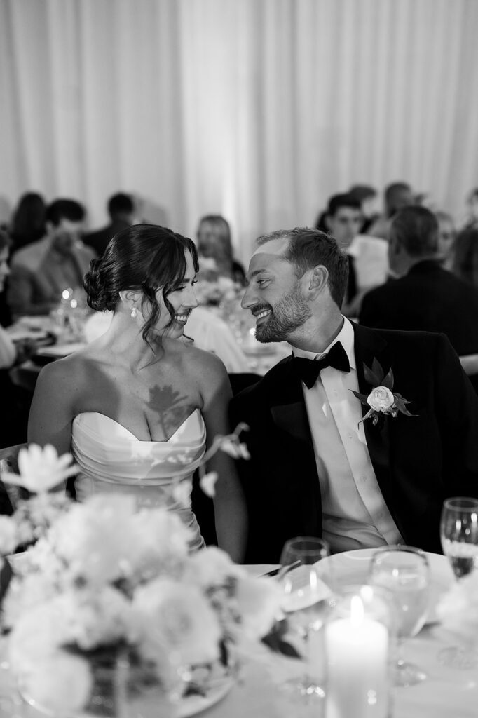 Bride and groom smiling at each other during their Bay Harbor Yacht Club wedding reception in Northern Michigan