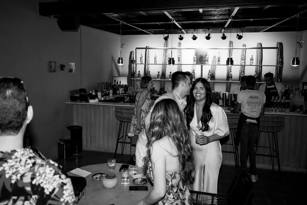 Black and white photo of guests mingling at Bekeb during a wedding welcome party