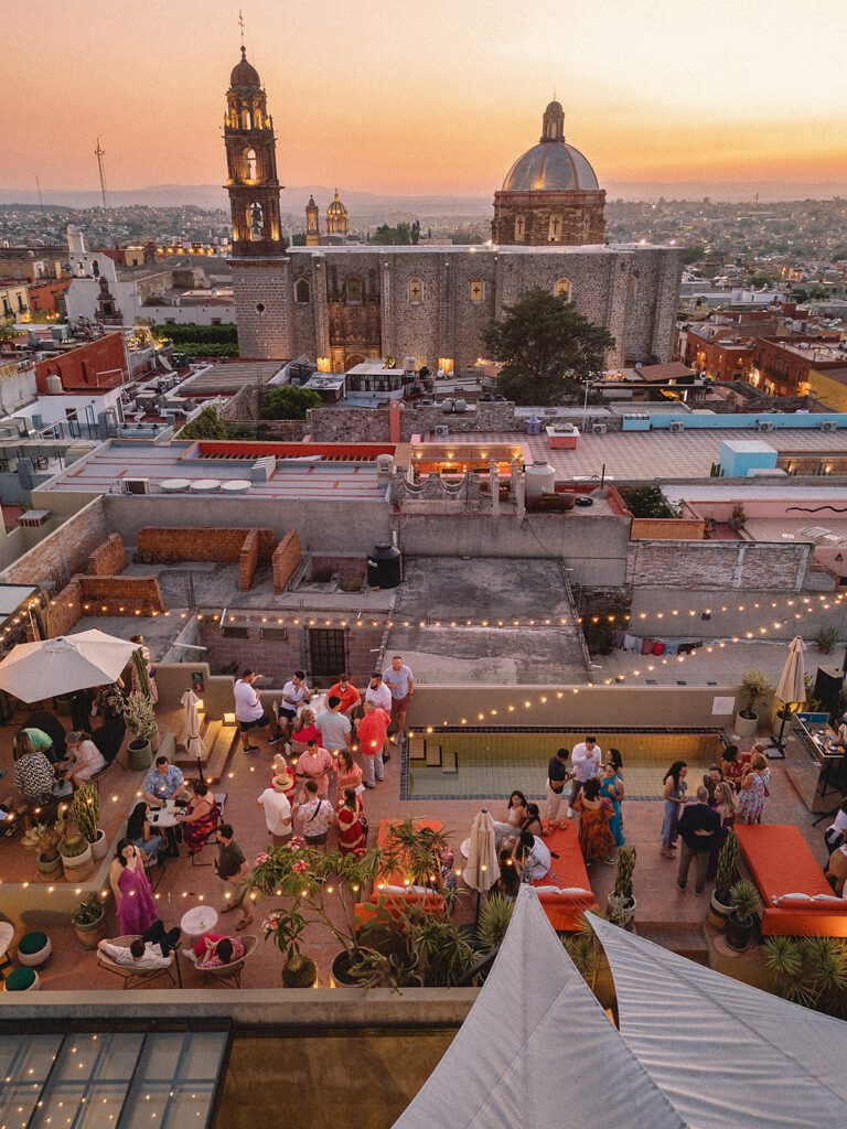Guests gather on the rooftop bar at Bekeb during a San Miguel de Allende wedding welcome party at sunset.