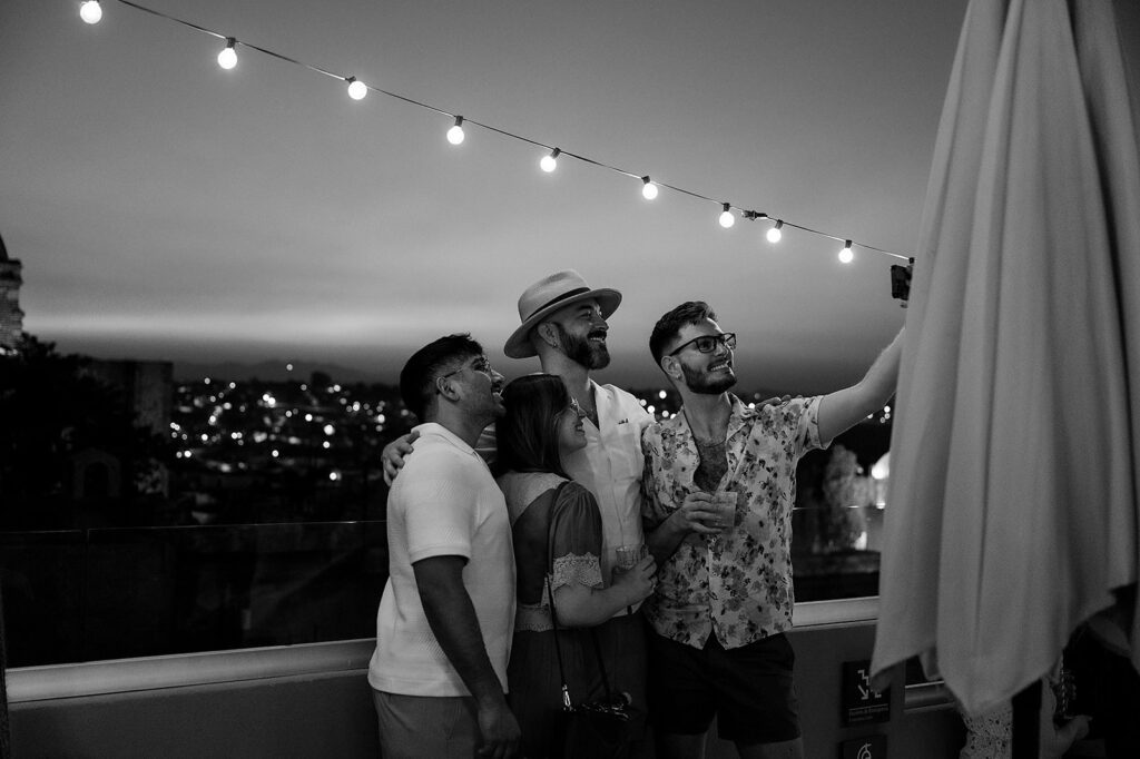 Guests take a selfie together under string lights overlooking the San Miguel de Allende skyline during the wedding weekend.