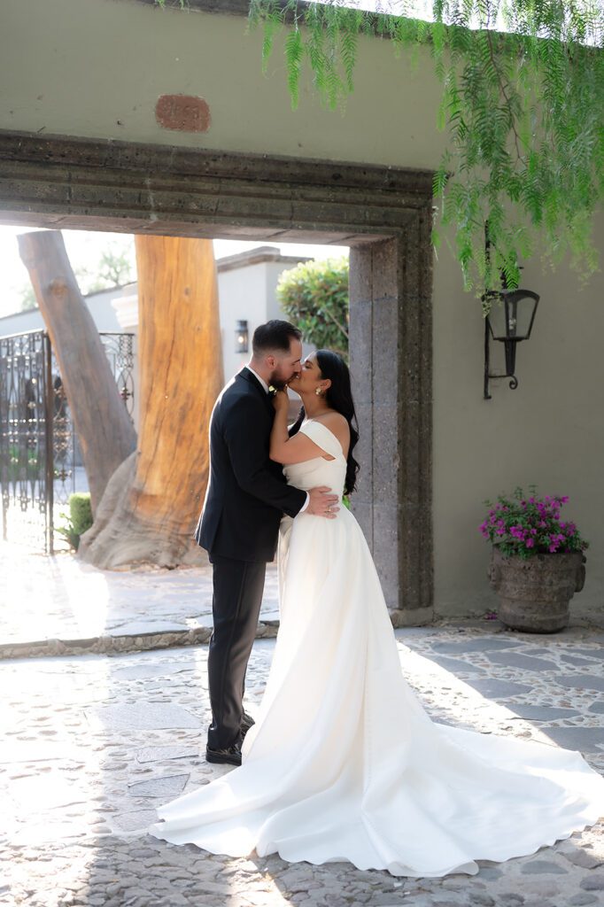 Bride and groom kissing under stone archway at Hacienda San Luis Gonzaga wedding