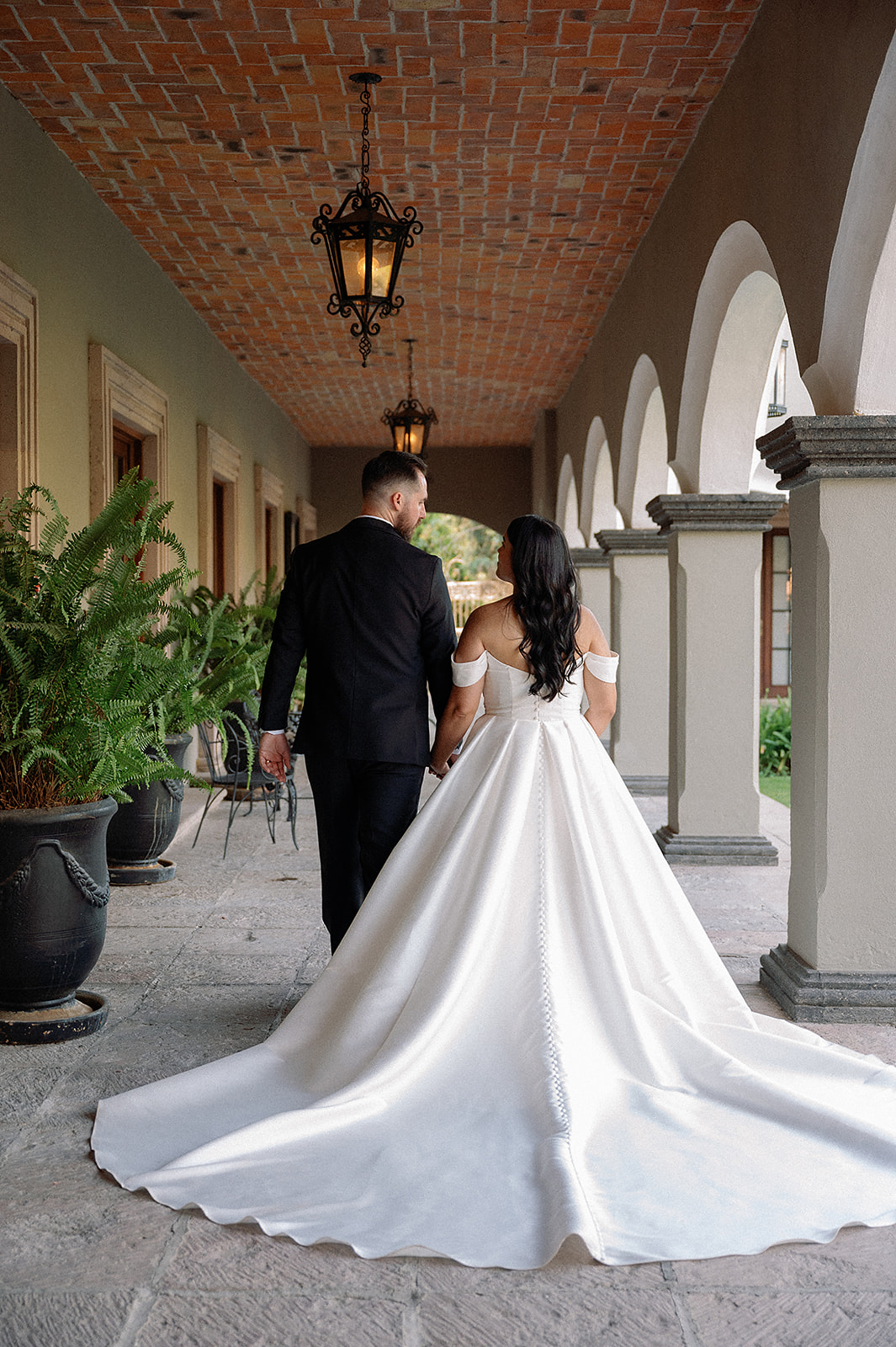 Bride and groom walking through arched hallway at Hacienda San Luis Gonzaga